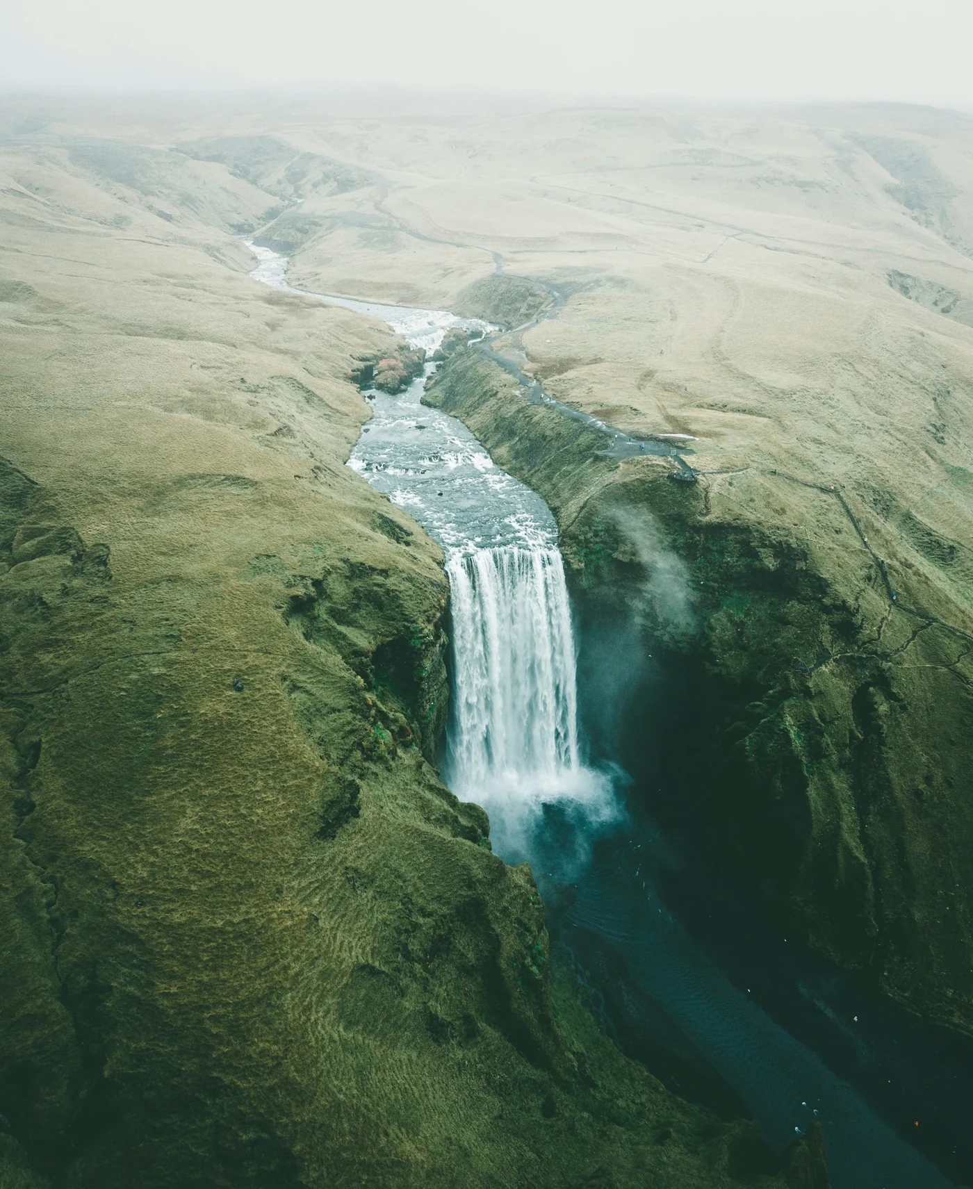 Skógafoss waterfall surrounded by green Icelandic terrain