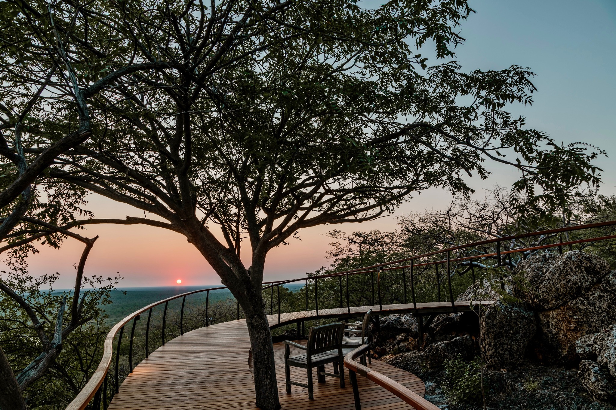A lodge walkway beneath mature trees at sunset