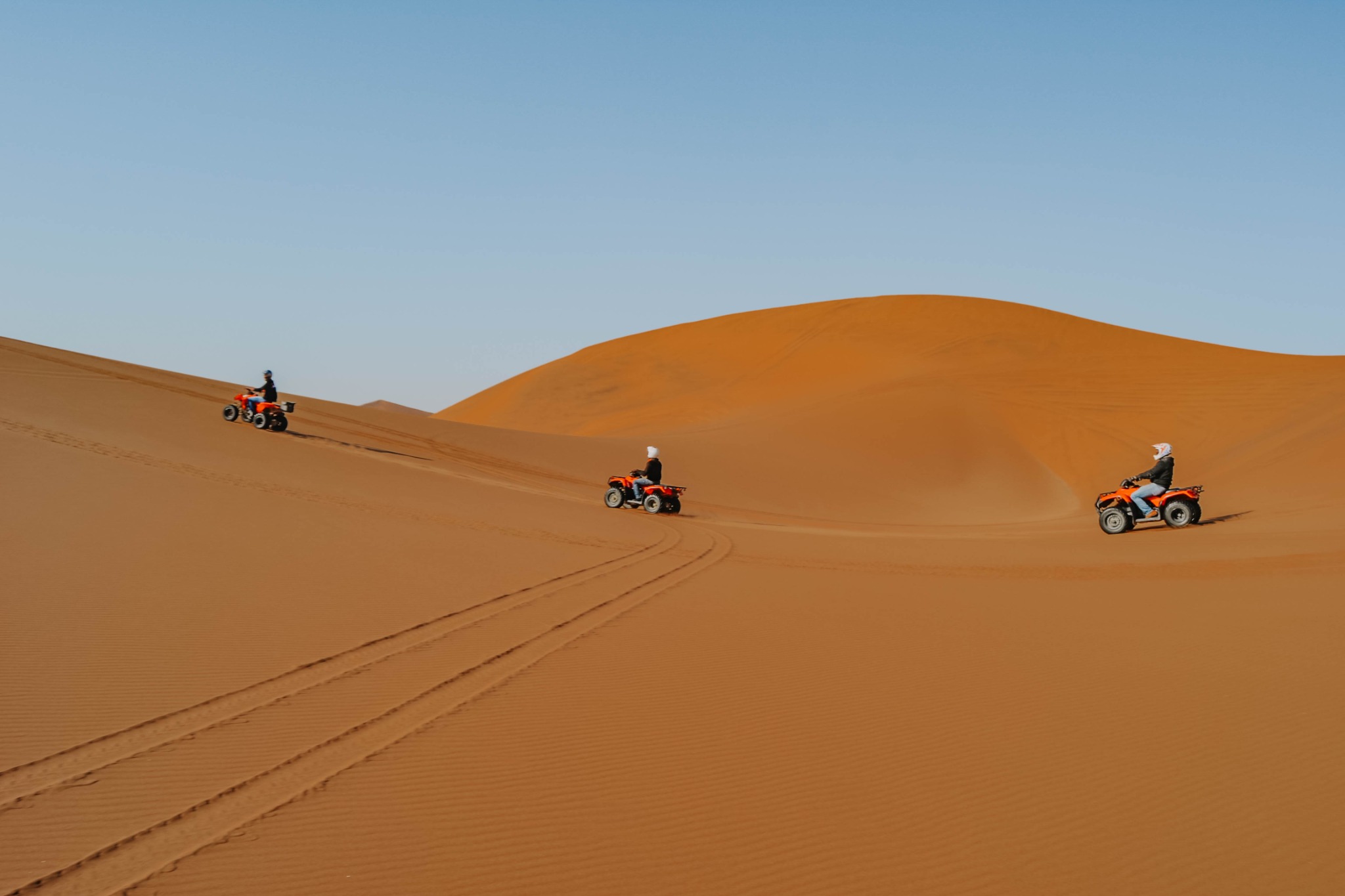Travellers riding quad bikes across Namibia’s desert dunes